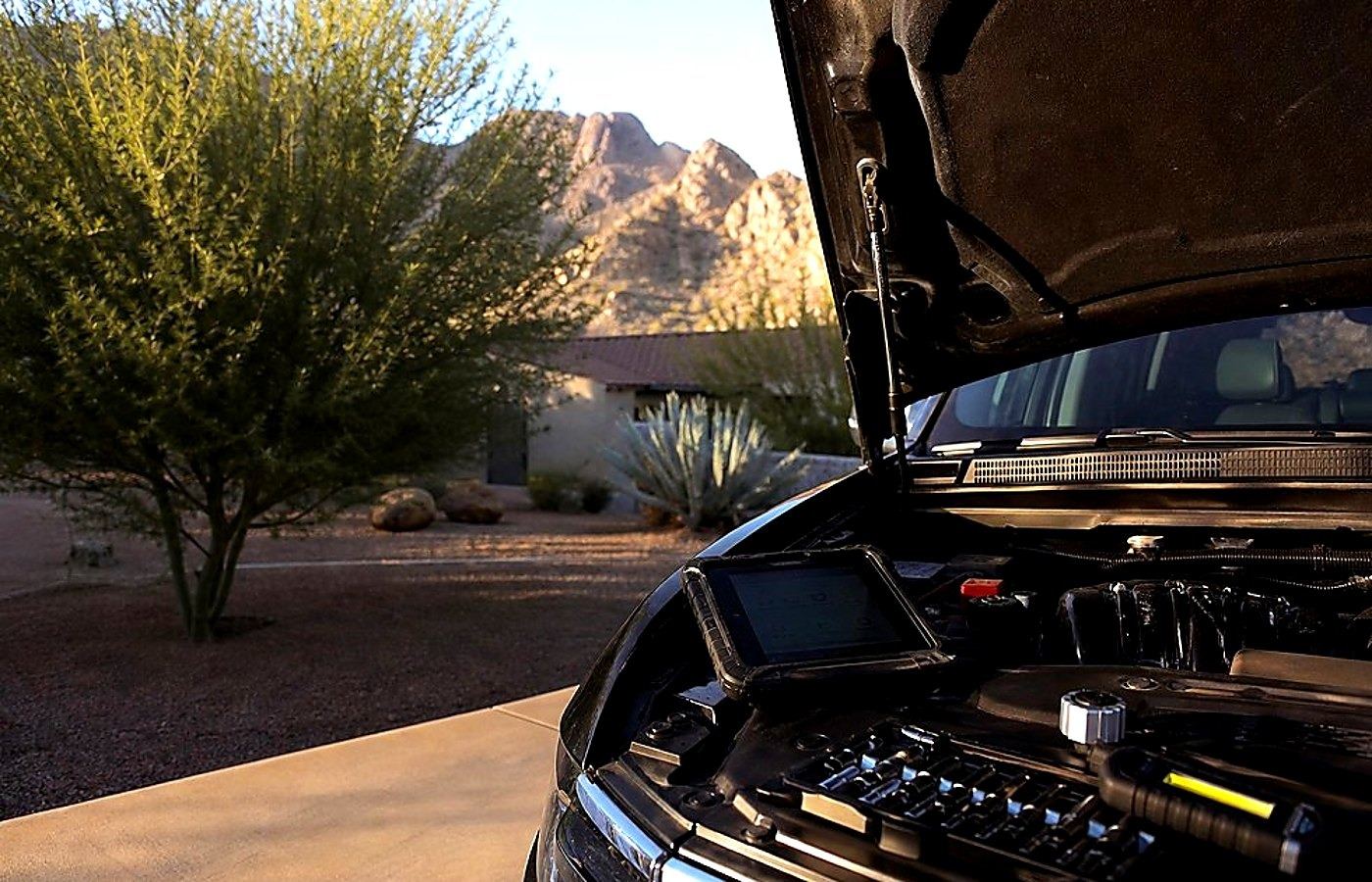 Huntington Beach mobile mechanic testing a battery in a sunny parking lot